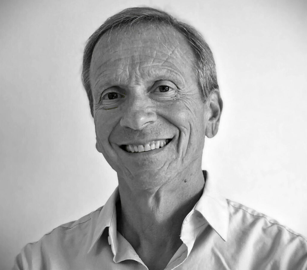 Uomo con camicia chiara e sorriso, in un ritratto in bianco e nero.