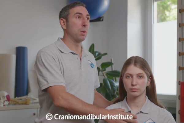 Un fisioterapista guida una giovane nella distrazione mandibolare monolaterale durante un esercizio riabilitativo.
