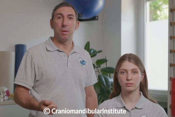 Un fisioterapista e una giovane donna mostrano l’esercizio di distrazione mandibolare bilaterale in ambulatorio.