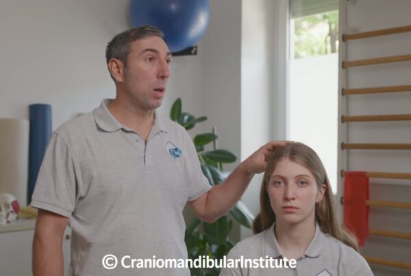 Fisioterapista guida una donna in un esercizio per le parafunzioni orali, con una mano appoggiata delicatamente sulla testa.